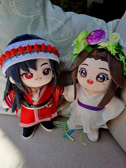 fafa minidoll with san lang's outfit, no eyepatch and a crocheted head band with red tulips standing next to lianlian with a flower crown of purple, green and yellow and a belt of purple and white dots