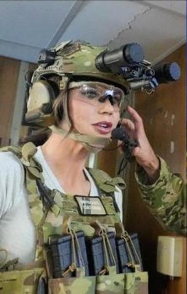 Kristi Noem in battle gear, a hemet, headphones, and night vision goggles.