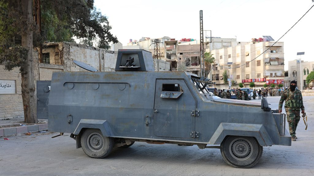Syrische ordetroepen met een groot pantservoertuig bij een controlepost in een voorstad van Damascus (foto: EPA)