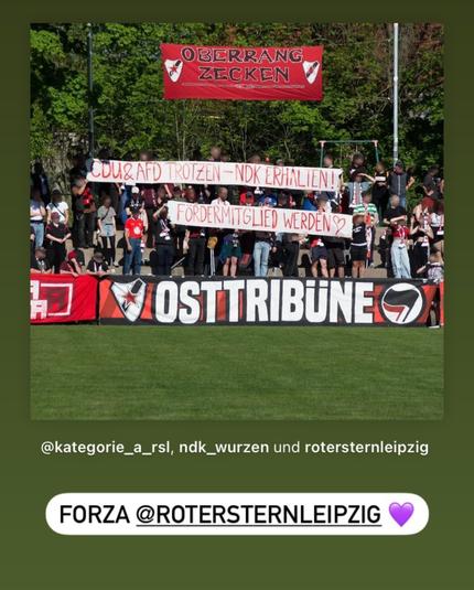 Das Bild zeigt eine Gruppe von Fußballfans auf einer Tribüne im Freien. Sie halten Transparente hoch mit den Aufschriften:

„CDU & AfD trotzen – NDK erhalten!“

„Fördermitglied werden [Herzsymbol]“


Im Hintergrund hängt ein rotes Banner mit der Aufschrift „OBERRANG ZECKEN“ und dem Logo des Vereins Roter Stern Leipzig. Unten vor der Tribüne ist ein weiteres Banner zu sehen: „OSTTRIBÜNE“ mit einem stilisierten Antifa-Logo.

In der unteren Bildunterschrift werden mehrere Instagram-Accounts markiert: @kategorie_a_rsl, ndk_wurzen und rotersternleipzig. Darunter steht in einer Sprechblase: „FORZA @ROTERSTERNLEIPZIG“ mit einem lilafarbenen Herz.

Die Szene drückt klare Solidarität mit dem NDK (Netzwerk für Demokratische Kultur) in Wurzen aus und stellt sich gegen rechte Parteien wie CDU und AfD. Es handelt sich um eine politische Stellungnahme aus dem linksalternativen Fußballumfeld.