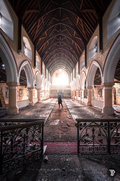 Dark silhouette in an abandoned church, light coming by broken stained glass
