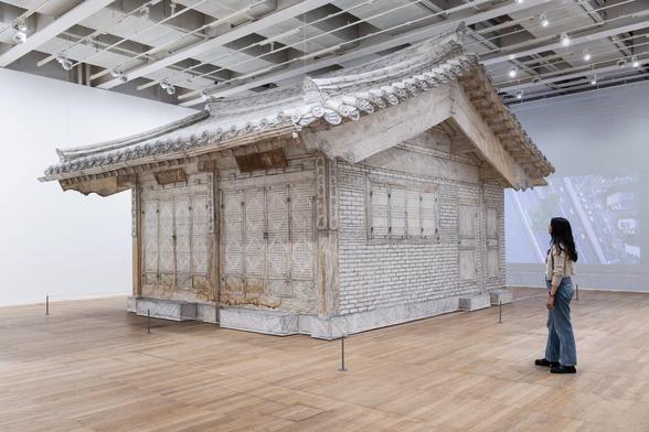 a life-size installation of a traditional Korean home made of white fabric in a gallery space