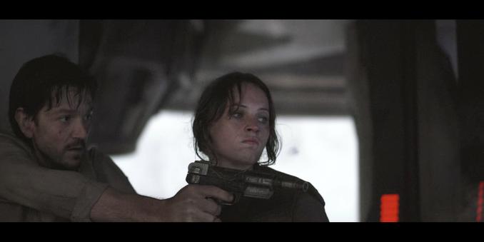 man holding blaster pistol next to woman (cassian and jyn in rogue one)
