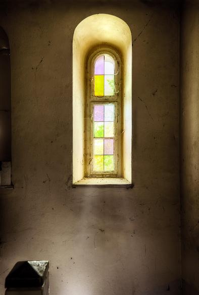 Ein kleines, sehr schmales Fenster mit bunten Scheiben.
