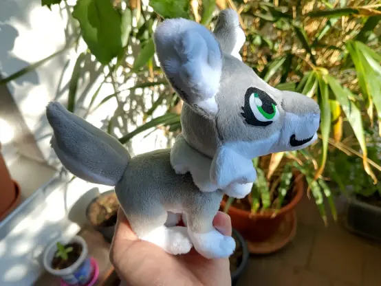 Me holding a pocket sized grey wolf plushie with my oversized bamboo in the background.