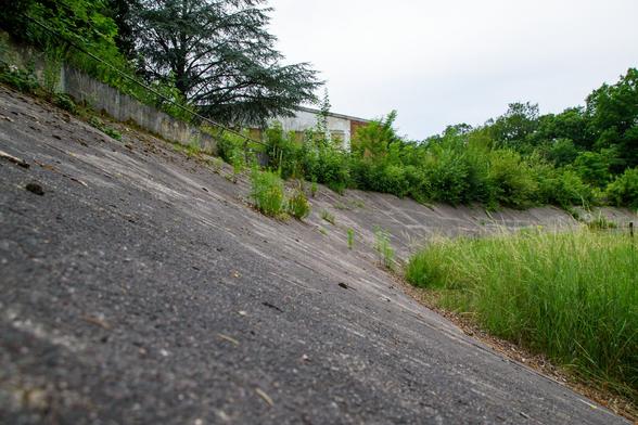 picture of an abandoned bike race track. the picture is taken from directly above the track. the frame is level while the curve of the track is not.
Theres grass on the track and a small building in the background