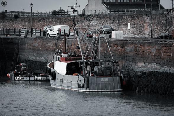 Old trawler and small boats at dock