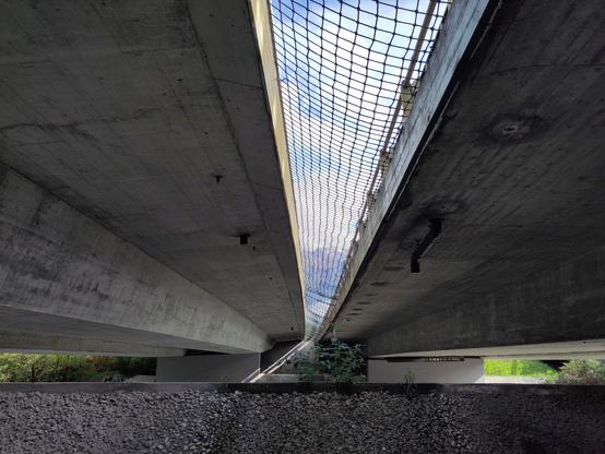 Foto. Zwei Betonbrücken, der Spalt dazwischen ist mit einem Netz geschlossen.