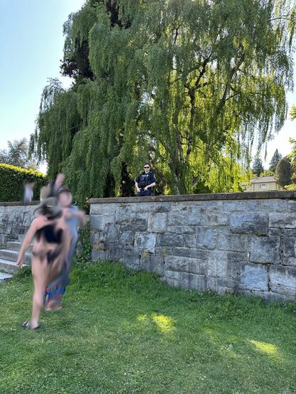 A cop perched behind a ledge looks menacingly at the camera person with his hands on his gun belt