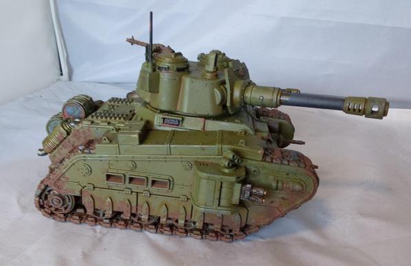 A big, green, somewhat dirty tank with a lot of guns. Side view.