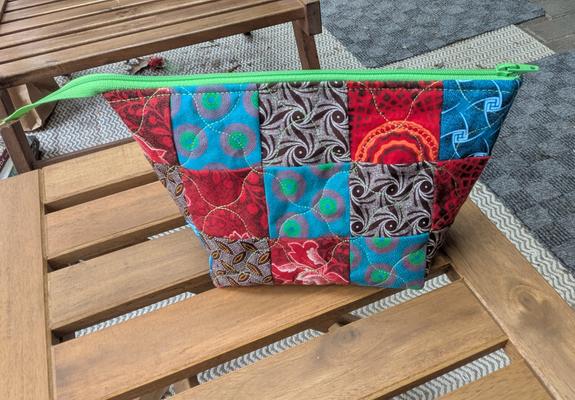 A patchwork zipper pouch using scraps in red, turquoise and brown.