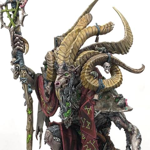 Huge, multi-horned rat demon walking upright over green-glowing ruins surrounded by skittering rats. He carries a staff, has a sword at his hip, and wears red robes and a sash. All are glowing with green runes, including Vizzik’s back.