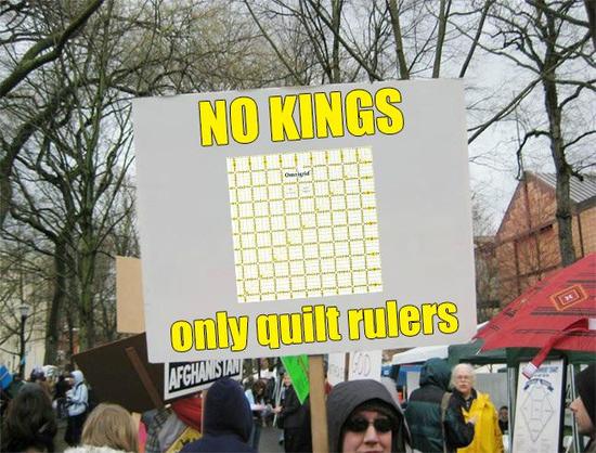 Large protest sign with a picture of an Omnigrid quilt ruler on it and text "NO KINGS only quilt rulers"