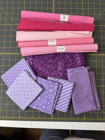 Stack of 11 fabrics, in various shades of pink and purple