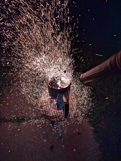 A chimney full of hot charcoal, fanned by a leaf blower, throwing tons of sparks.
