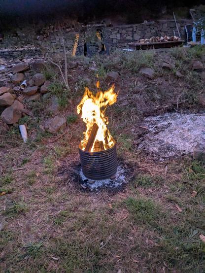 Backyard fire next to a Rockwall. The fire is contained in the inner stainless steel cylinder which was salvaged from a broken washing machine.