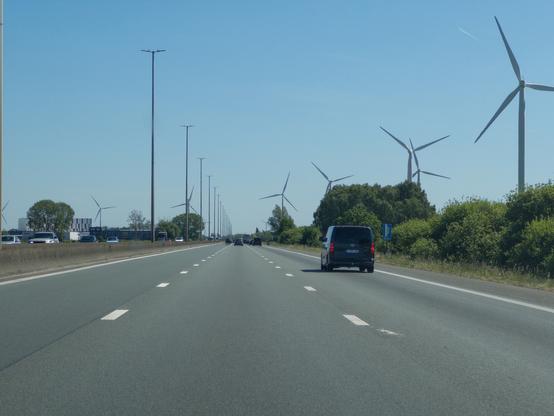 A highway lined with wind turbines under a clear blue sky.