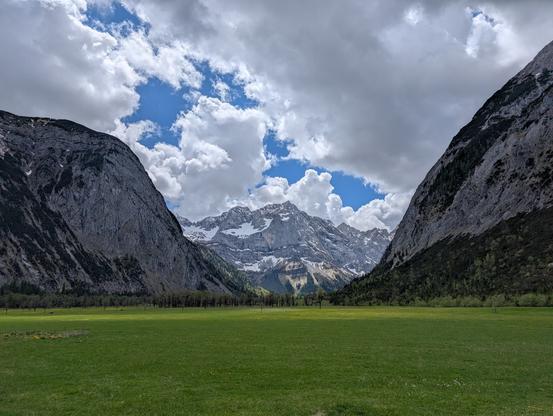 Der Große Ahornboden umrandet von Bergen. Bewölkter Himmel.