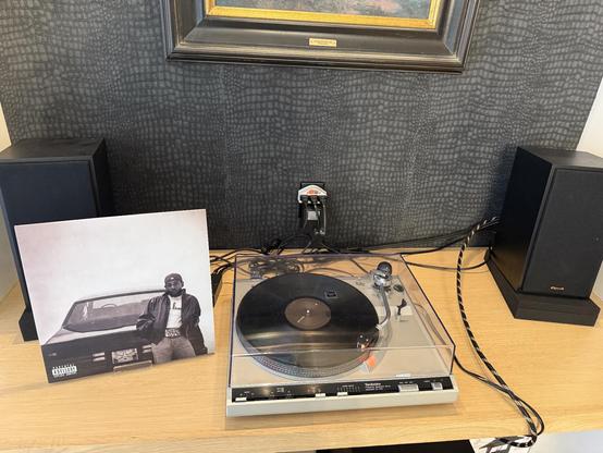 A photo of GNX by Kendrick Lamar Vinyl art next to a record player and speakers.