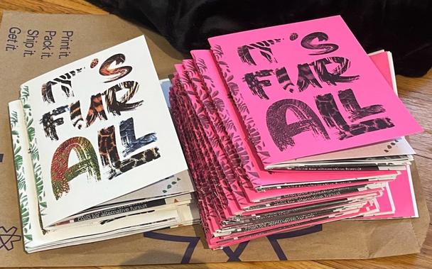 Stacks of It's Fur All zines on a table.