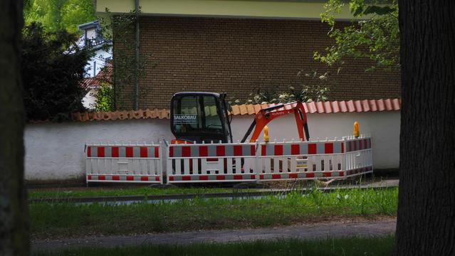 Kleinbagger hinter rotweißen Absperrungen