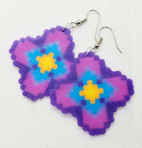 a pair of perler beaded earrings made by kiamichi in pink and purple with bright blue and yellow centers