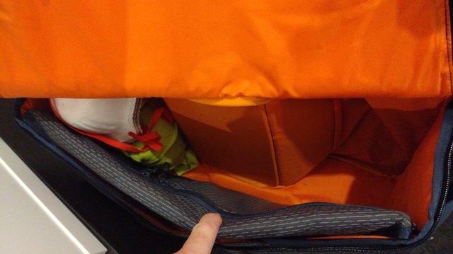 Blick von schräg vorne oben ins orangefarbene Innere der Fronttasche. Man sieht, dass sich der Deckel nicht ganz öffnen lässt.