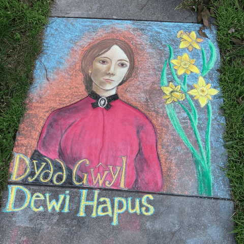 Chalk art on pavement, based loosely on the self-portrait of Welsh artist Gwen John, plus four daffodils and the caption "Dydd Gwyl Dewi Hapus".
