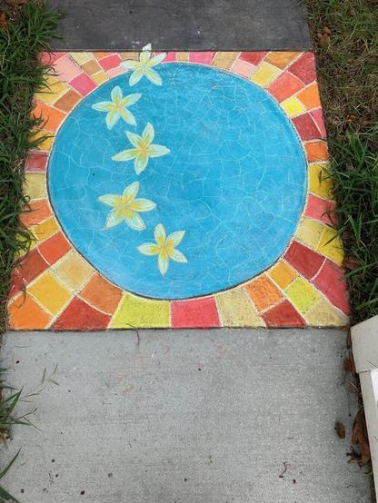 A chalk drawing on pavement, featuring a round blue pool surrounded by warm colored bricks or tiles, with five floating plumeria blossoms