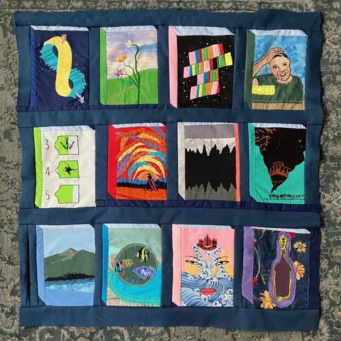 A quilt top with fabric applique and embroidered interpretations of twelve book covers (list in main post). With dark blue sashing.