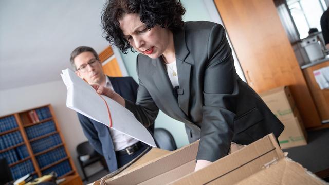 Amira Mohamed Ali steht in einem Büro und legt einen Karton mit Wahlbeschwerdeunterlagen auf den Schreibtisch