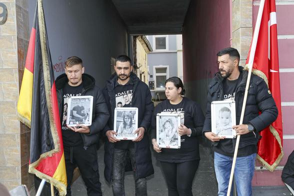 Vier Personen zeigen Fotos von einer Familie, die bei einem Brandanschlag ums Leben kamen Vier Personen zeigen Fotos von einer Familie, die bei einem Brandanschlag ums Leben kamen