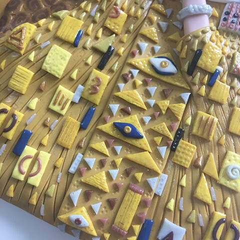 A close up of Adele's dress, ornately detailed with gold triangles and geometric shapes with a couple of eye symbols in there too 