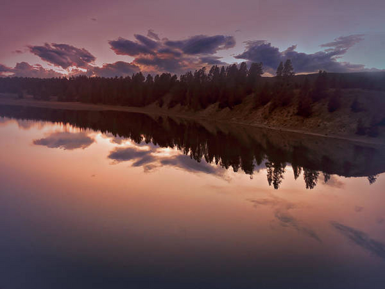 Yellowstone National Park Lake reflections at sunset in tones of orange, rust and navy blue here:

https://pixels.com/featured/yellowstone-lake-autumn-reflections-norma-brandsberg.html