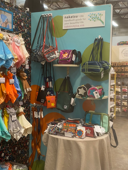 Vending booth display of brightly colored vinyl purses and bags by Nakatsu by JNA Designs