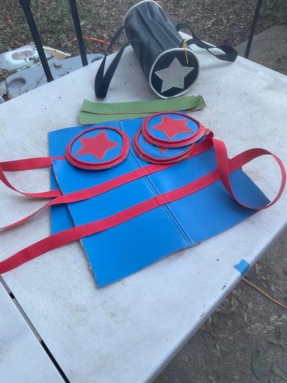 Parts for a vinyl bag being assembled, blue, red, green pieces, and a finished black and white tube duffel shaped purse