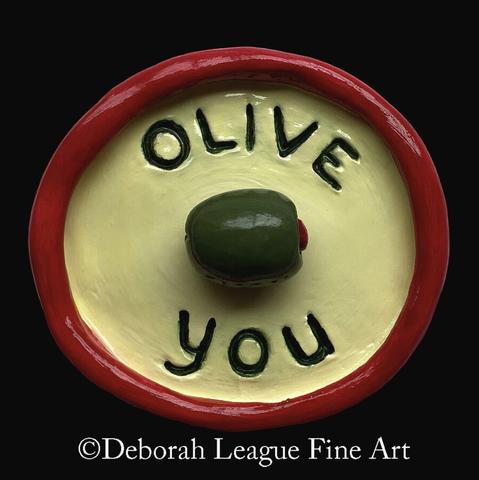 Bring a playful pop of humor to your space with this charming “Olive You” art print. Featuring bold colors, a whimsical design, and a clever food pun. This colorful print makes a perfect addition to kitchens, dining areas, or gallery walls. Ideal as a thoughtful gift for food lovers, pun enthusiasts, or anyone who appreciates quirky, heartfelt gifts.

A circular clay dish features a pun with the words "OLIVE YOU" surrounding a raised olive shape on a yellow background, all encircled by a red border. The design creatively combines wordplay and visual elements to convey a message of affection.