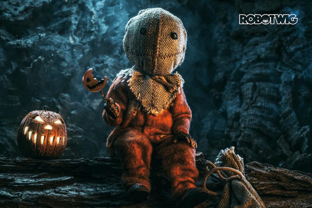 Sam sits on a log, lollipop in hand in a cave with a jack-o'-lantern next to him