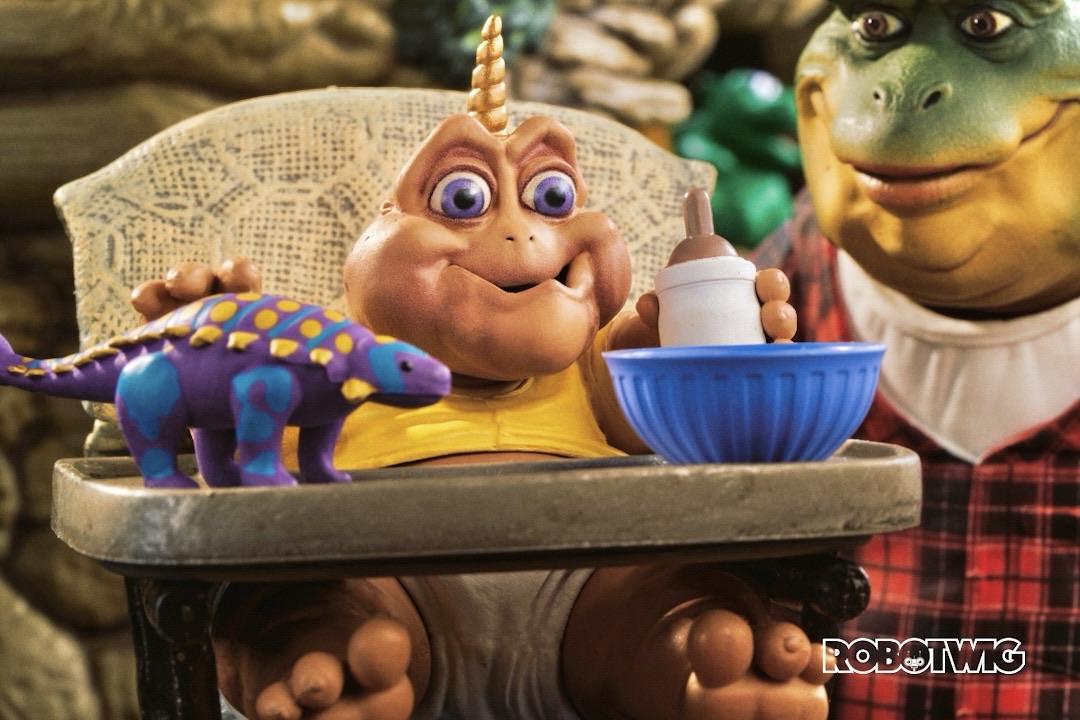 Baby Sinclair sits in his high chair with a golden unicorn type horn growing in it of his head. Based on a classic episode of dinosaurs