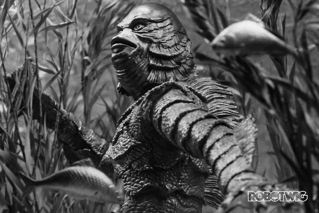 The creature from the black lagoon lurks underwater looking up to the surface surrounded by reeds and fish