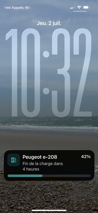 Capture d’écran de l’écran de verrouillage d’iOS, avec une activité en direct présentant le statut de chargé de ma voiture (charge actuelle et temps de charge restant).