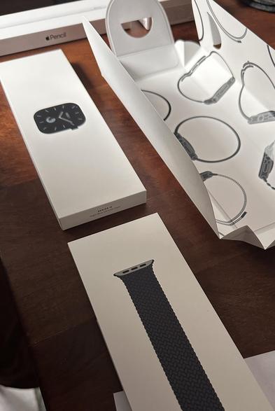 Apple Watch Box next to Apple Watch Band Box next to bigger wrapper with watch print