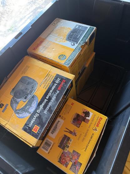 A bunch of 2000s era Kodak digital camera boxes in a large storage crate