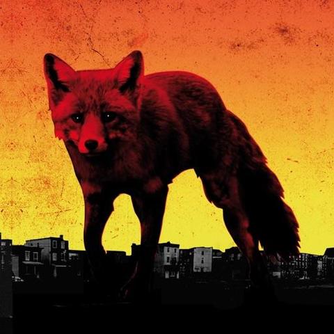 Album art of The Day Is My Enemy by the Prodigy. A giant fox against an orange sky, the city skyline darkening below her.