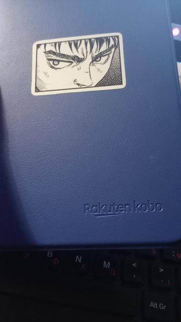 A close-up of the blue sleepcover of the eReader with a sticker on it of Guts from Berserk.