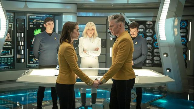 Captain Marie Batel and Captain Christopher Pike holding hands, looking into each other's eyes during a briefing with the crew of the USS Enterpise (Star Trek: Strange New Worlds 3x10, New Life and New Civilizations).