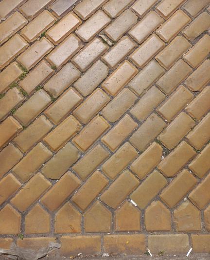 Yellow brick pavement. Some cigarette butts and nylon rags along with gunk and dirt.