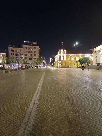 The yellow bricks road in the city centre of Sofia, Bulgaria, at midnight during a no-cars weekend. The building of the Bulgarian Academy of Sciences and part of the old Parliament building are visible to the right in the distance