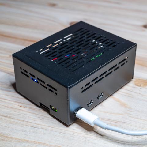 Schrägansicht des fertigen Smart-Home-Servers: Ein kompakter Raspberry Pi 5 mit Geekworm X1001 NVMe-Shield im mattschwarzen Geekworm P579-V2 Aluminiumgehäuse. Zu sehen sind die seitlichen Lüftungsschlitze für den Argon THRML Aktivkühler, zwei Micro-HDMI-Ports und die Stromversorgung über das angeschlossene USB-C-Kabel.