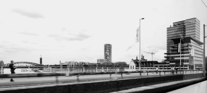 Black and white image of an urban skyline with modern buildings, a bridge, and a blurred figure of a person running.
